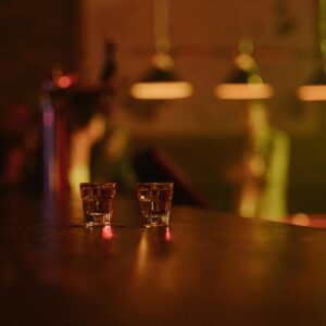 Two tequila shots on a dimly lit bar counter, creating a warm, inviting atmosphere in a bar setting.